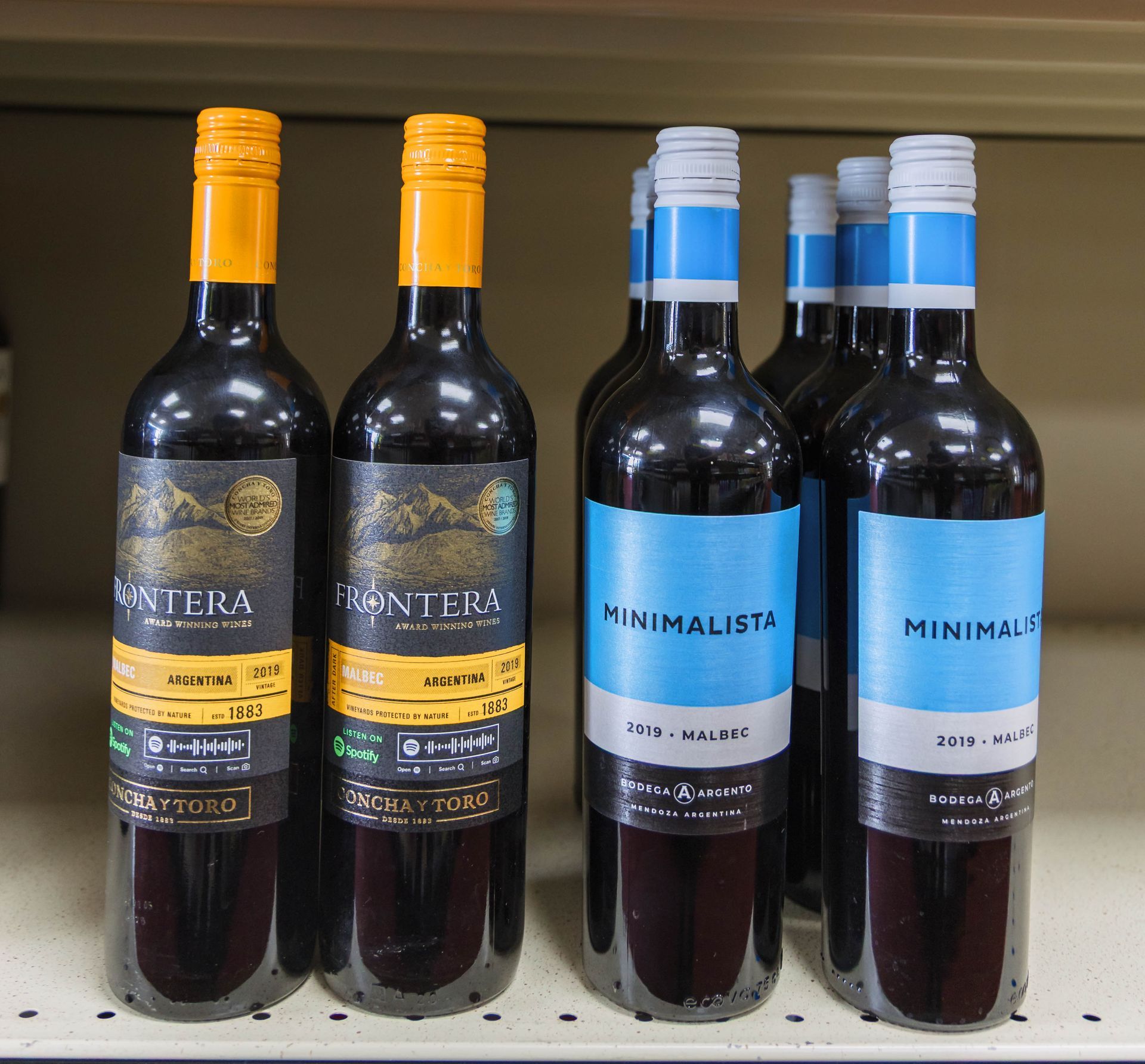 Bottles of red wine on a shelf with colorful labels, including