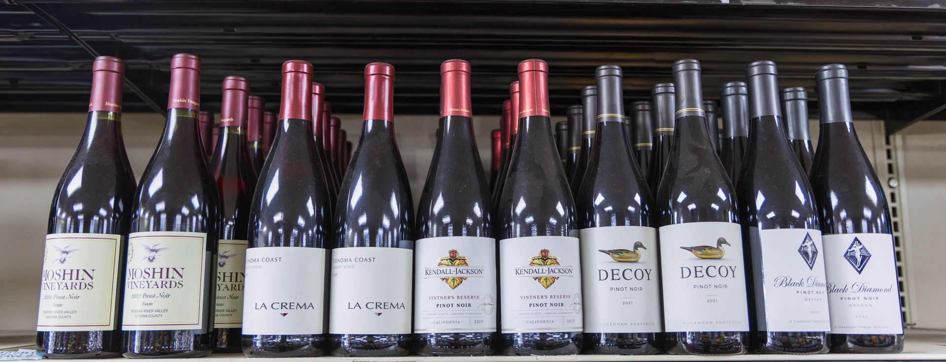 Bottles of red wine with various labels on a shelf.
