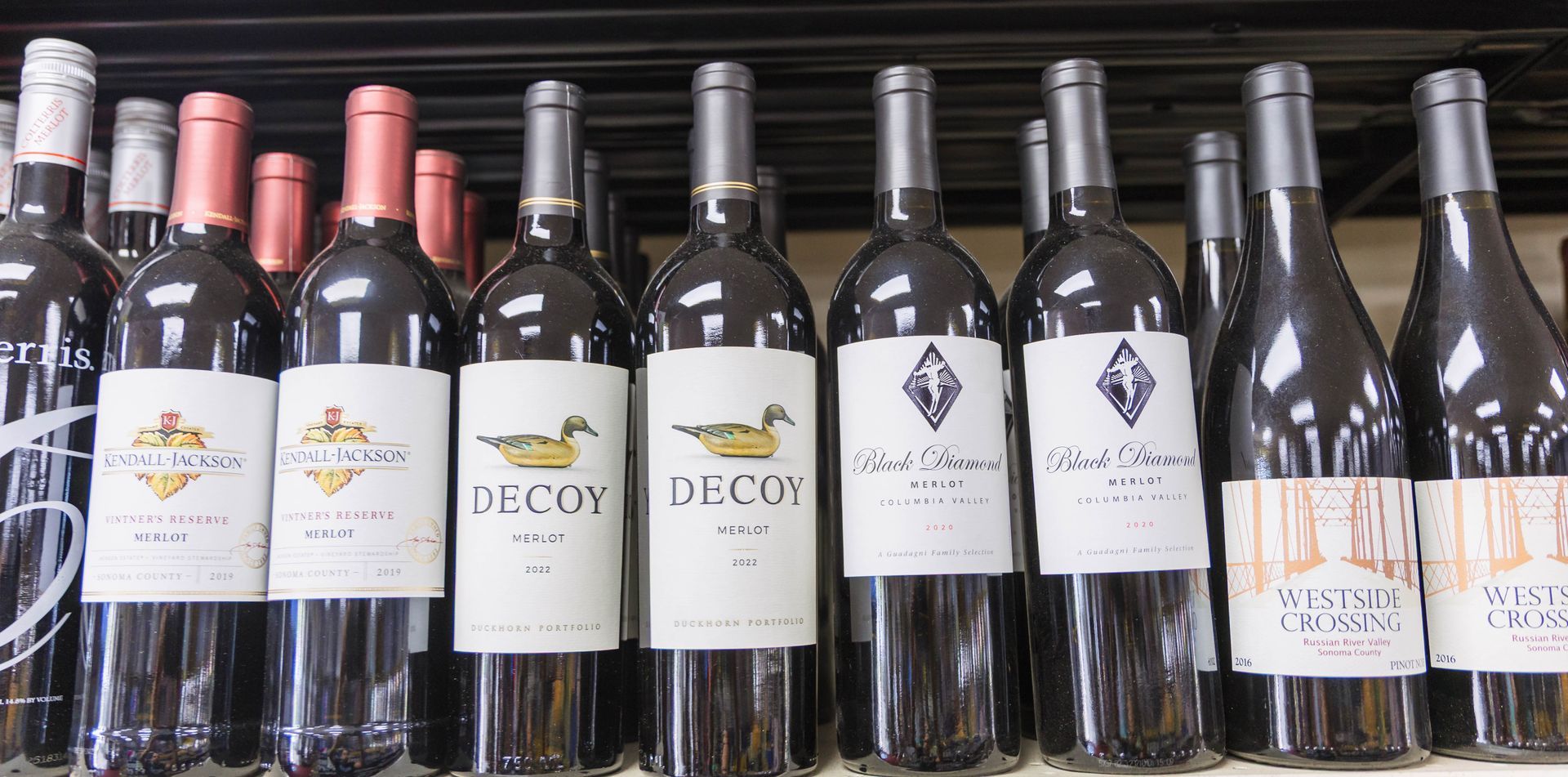 Wine bottles on a shelf, featuring labels with duck and diamond logos.