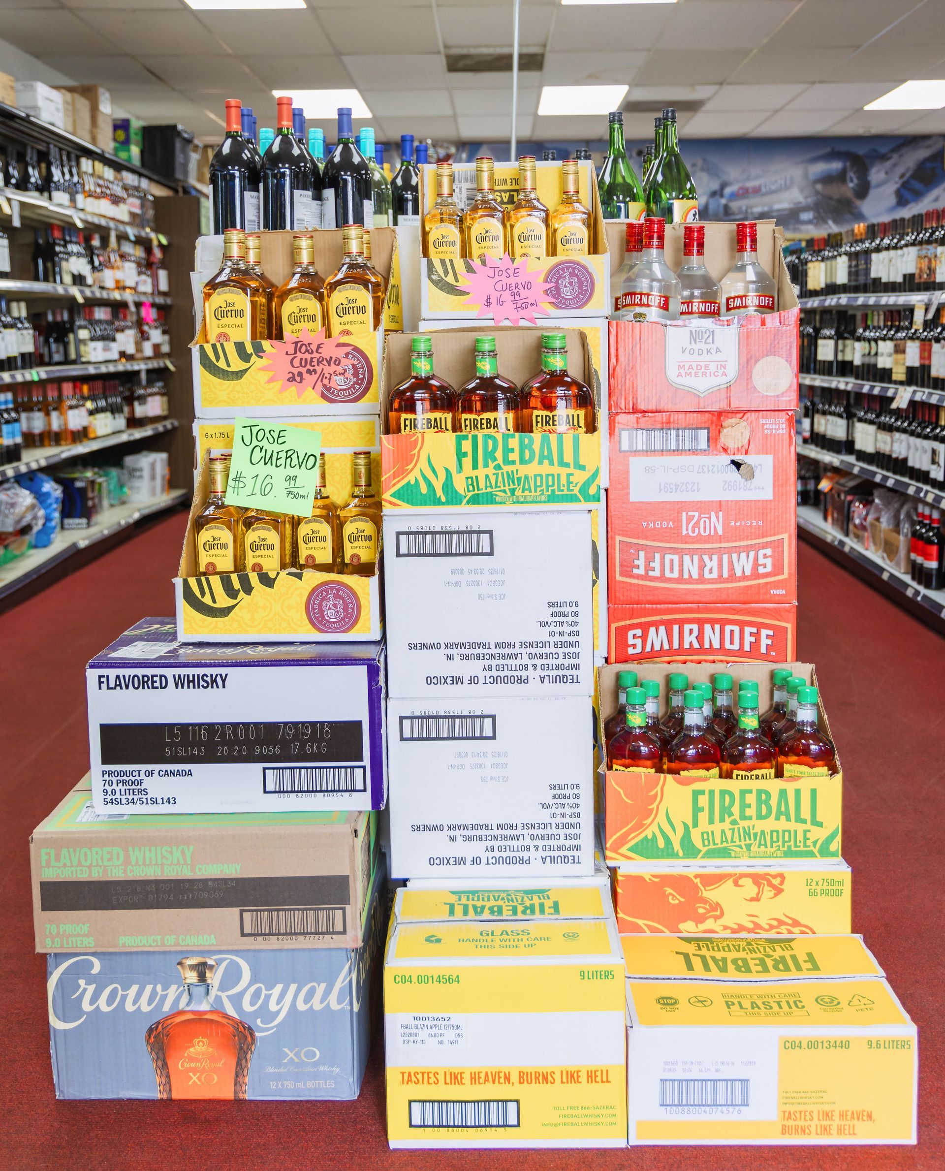 Liquor store display featuring stacked boxes of various alcoholic beverages including Fireball and Crown Royal.