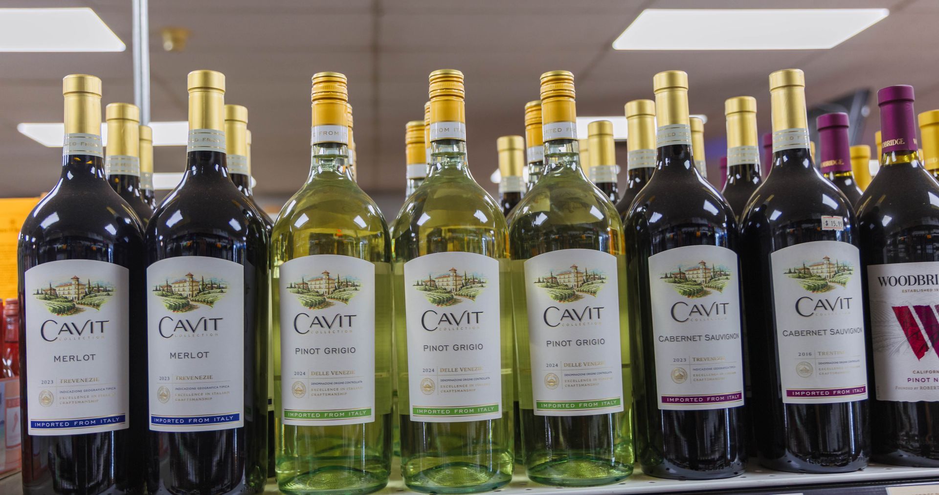Bottles of Cavit wine on a store shelf: red and white bottles with gold caps and labels.