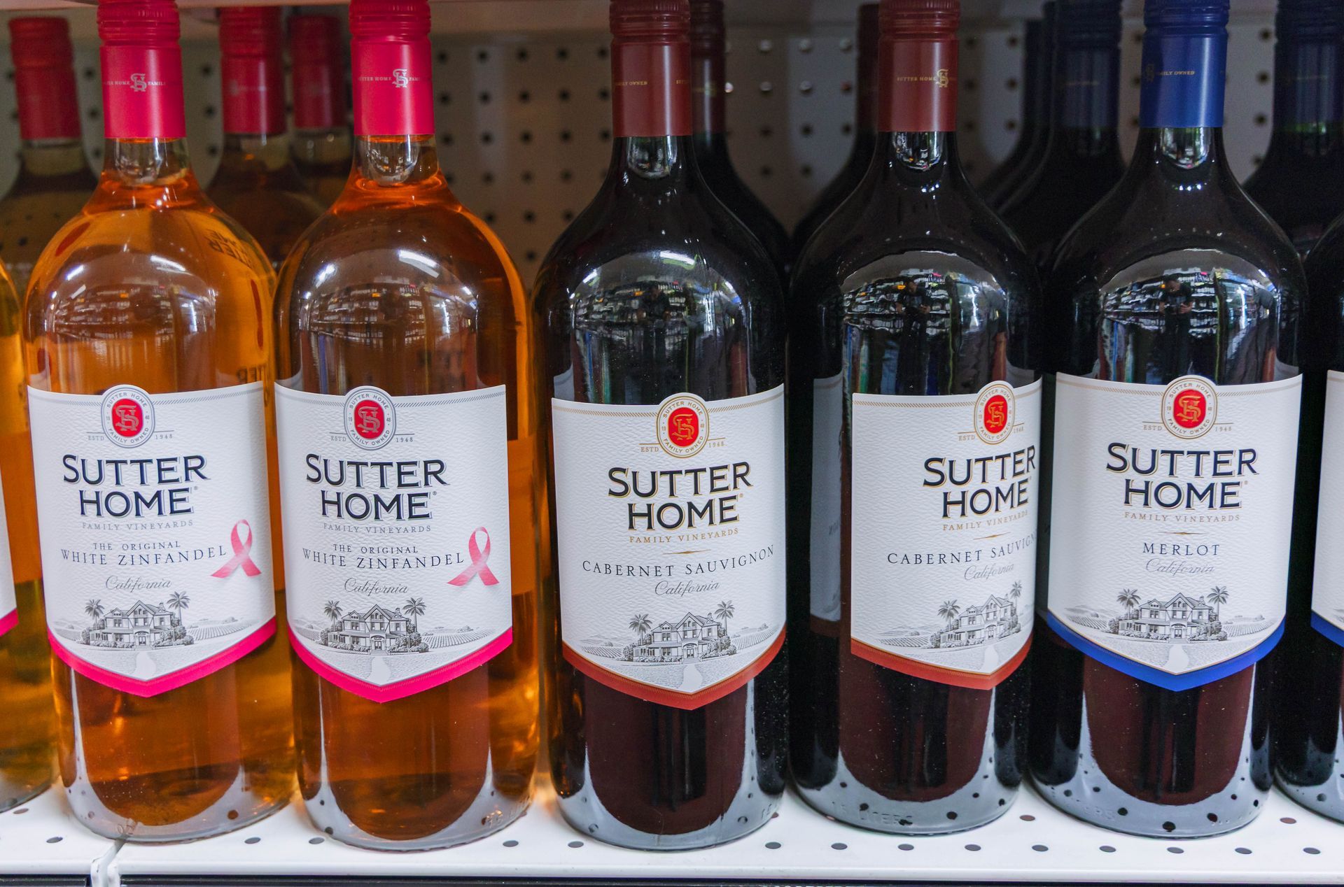 Bottles of Sutter Home wine on a shelf: rosé, red, and white wines.
