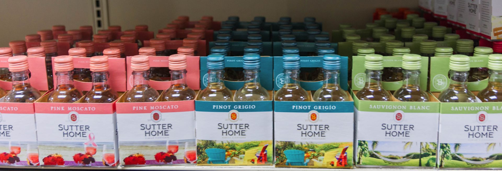 Bottles of wine in assorted colors on a shelf. Each box says