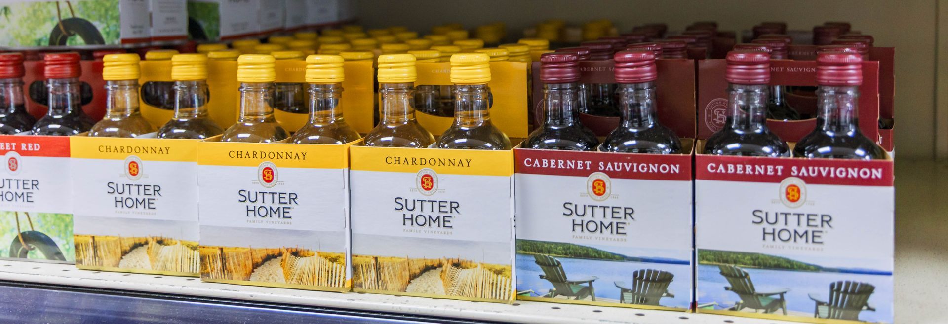 Wine bottles arranged in cardboard boxes on a shelf. Sutter Home brand wine is visible.