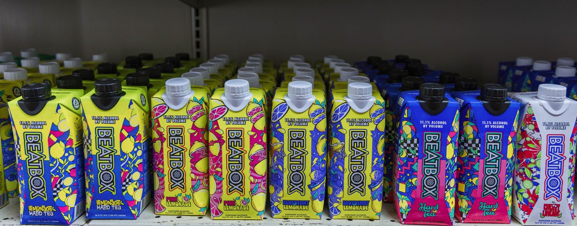 Rows of colorful juice boxes on a shelf, featuring vibrant designs, including yellow, blue, pink, and white.
