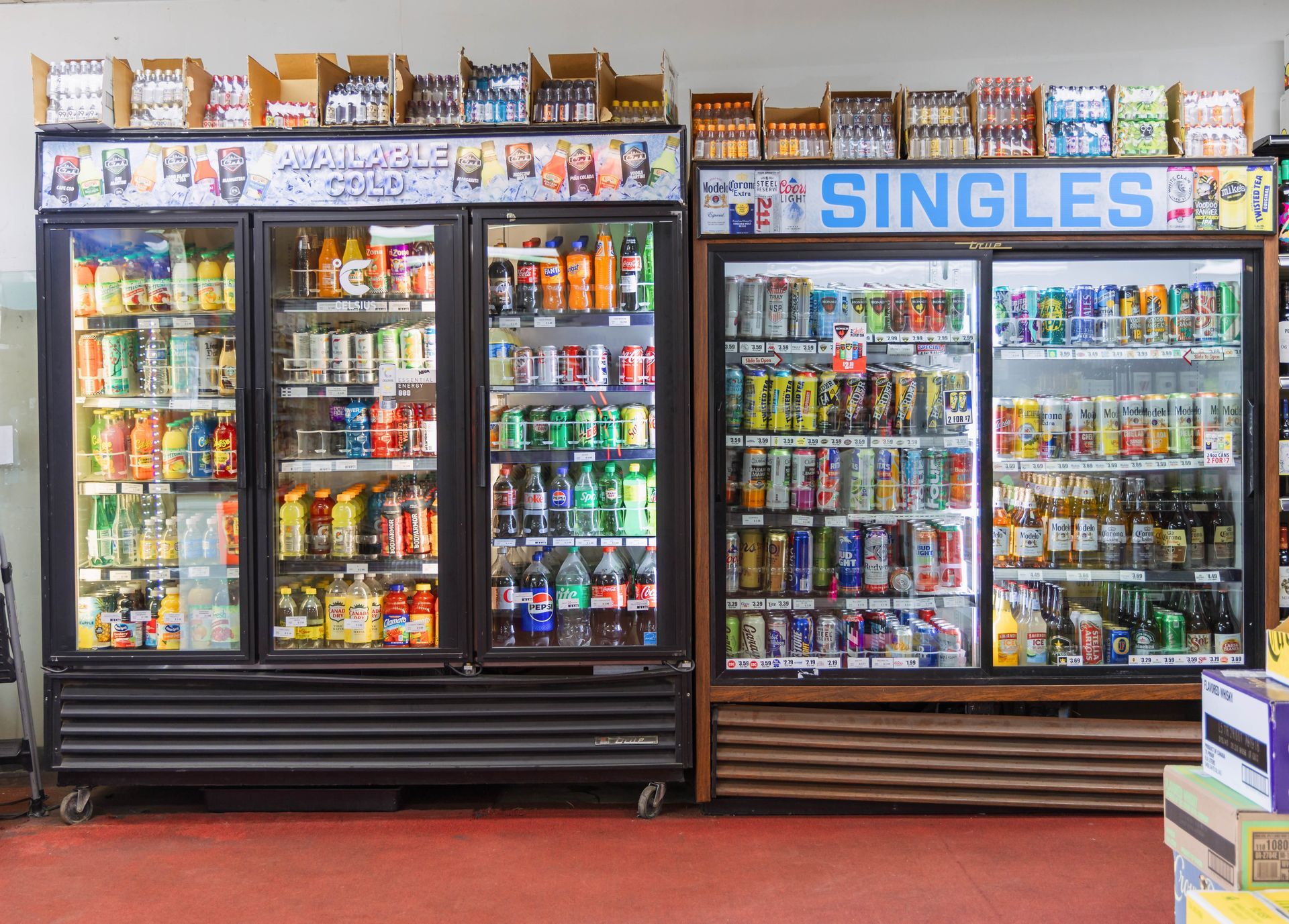 Refrigerated drink cases in a store, filled with beverages. One case labeled