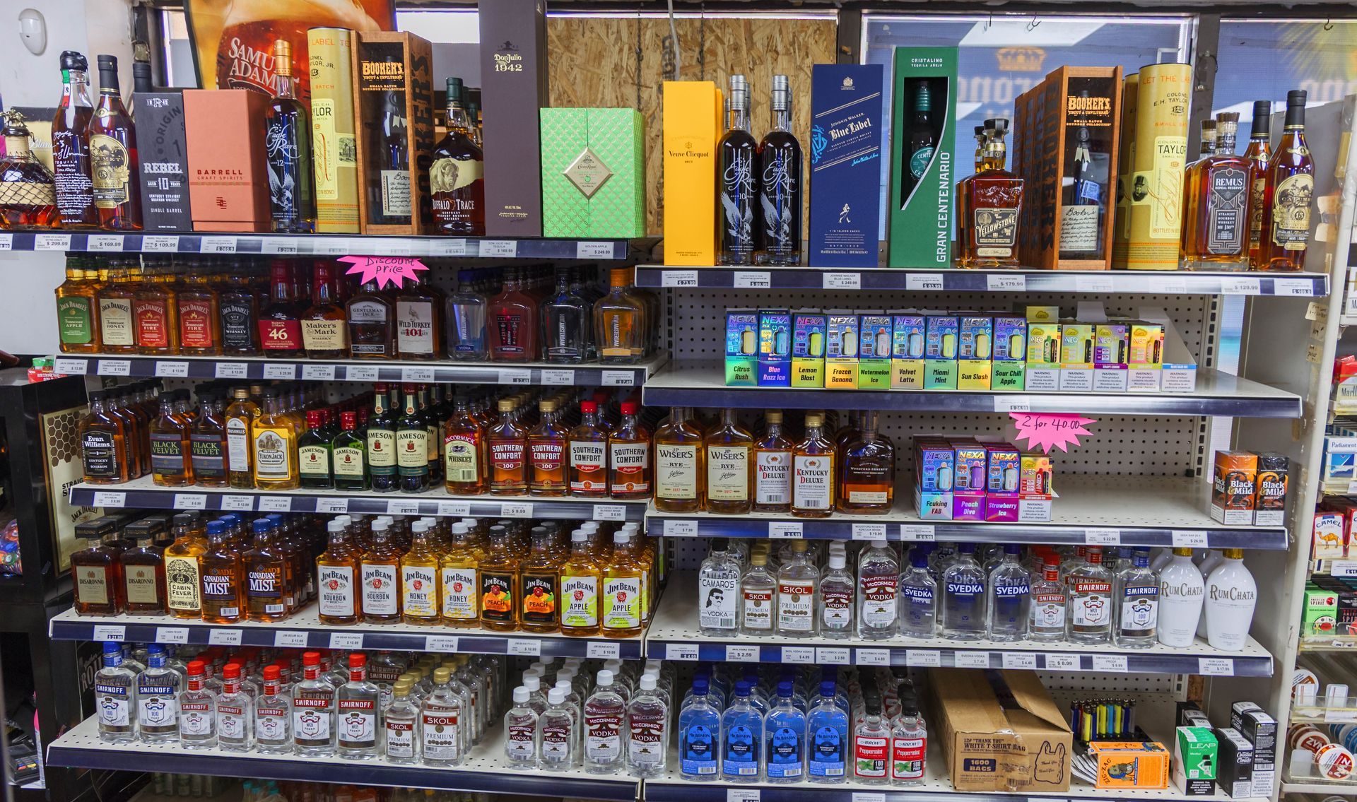 Shelves stocked with various liquor bottles in a store, including whiskeys, vodkas, and other spirits.