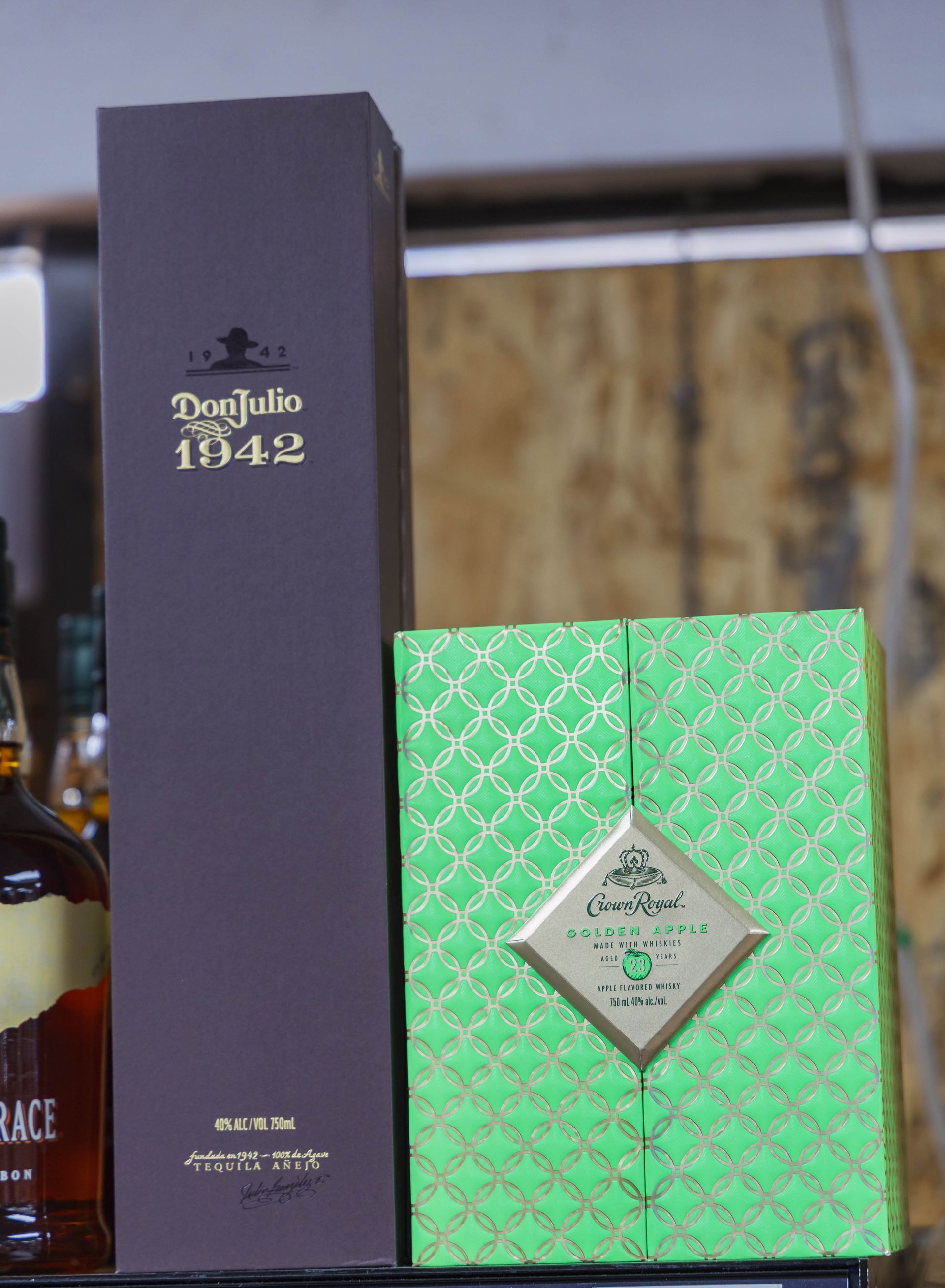 Don Julio 1942 bottle and green-boxed tequila on a shelf.