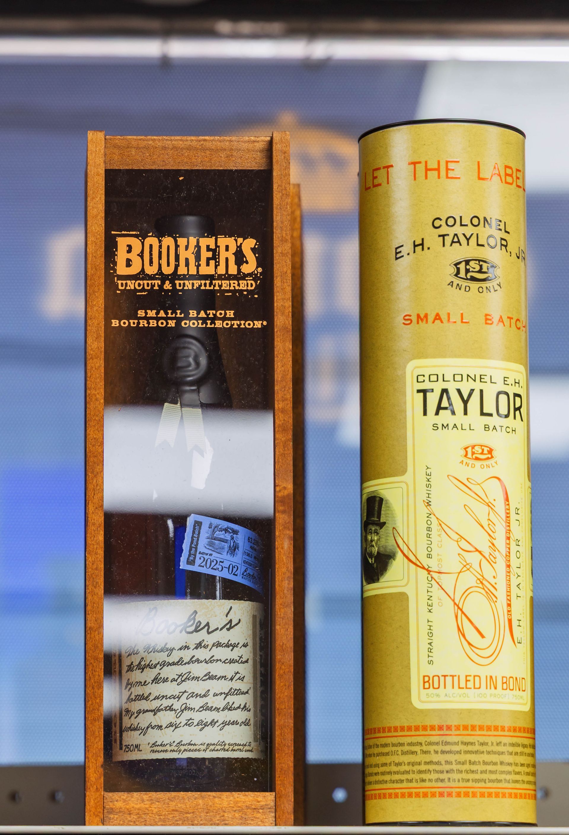 Booker's bourbon bottle in wooden box beside Colonel E. H. Taylor bourbon cylinder.
