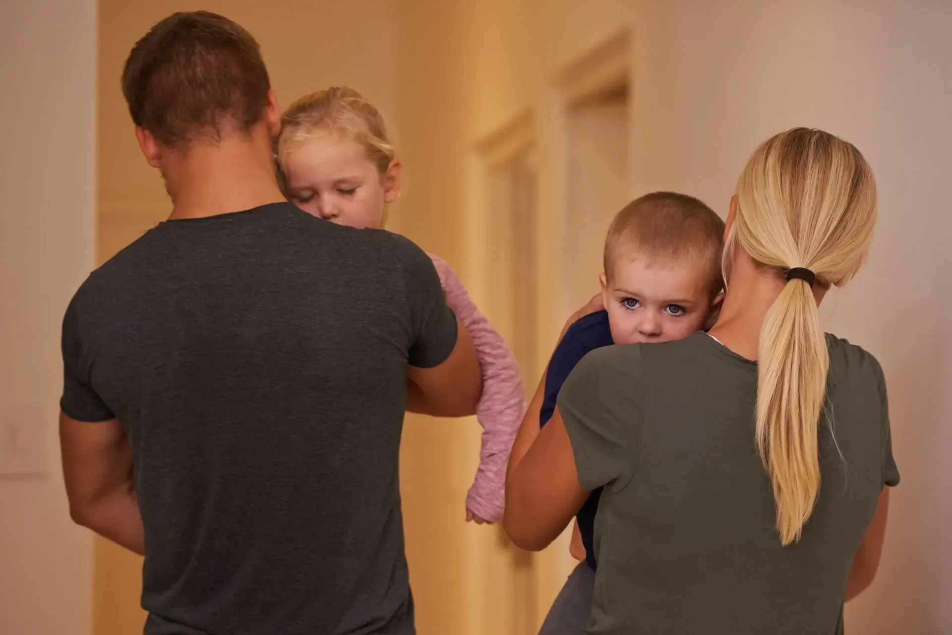 Parent are holding two children in their arms.