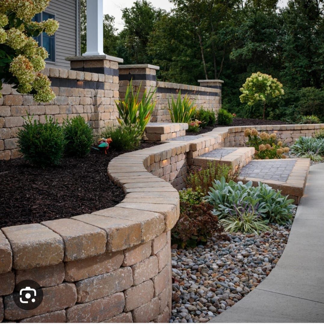 A brick walkway surrounded by plants and rocks leading to a house