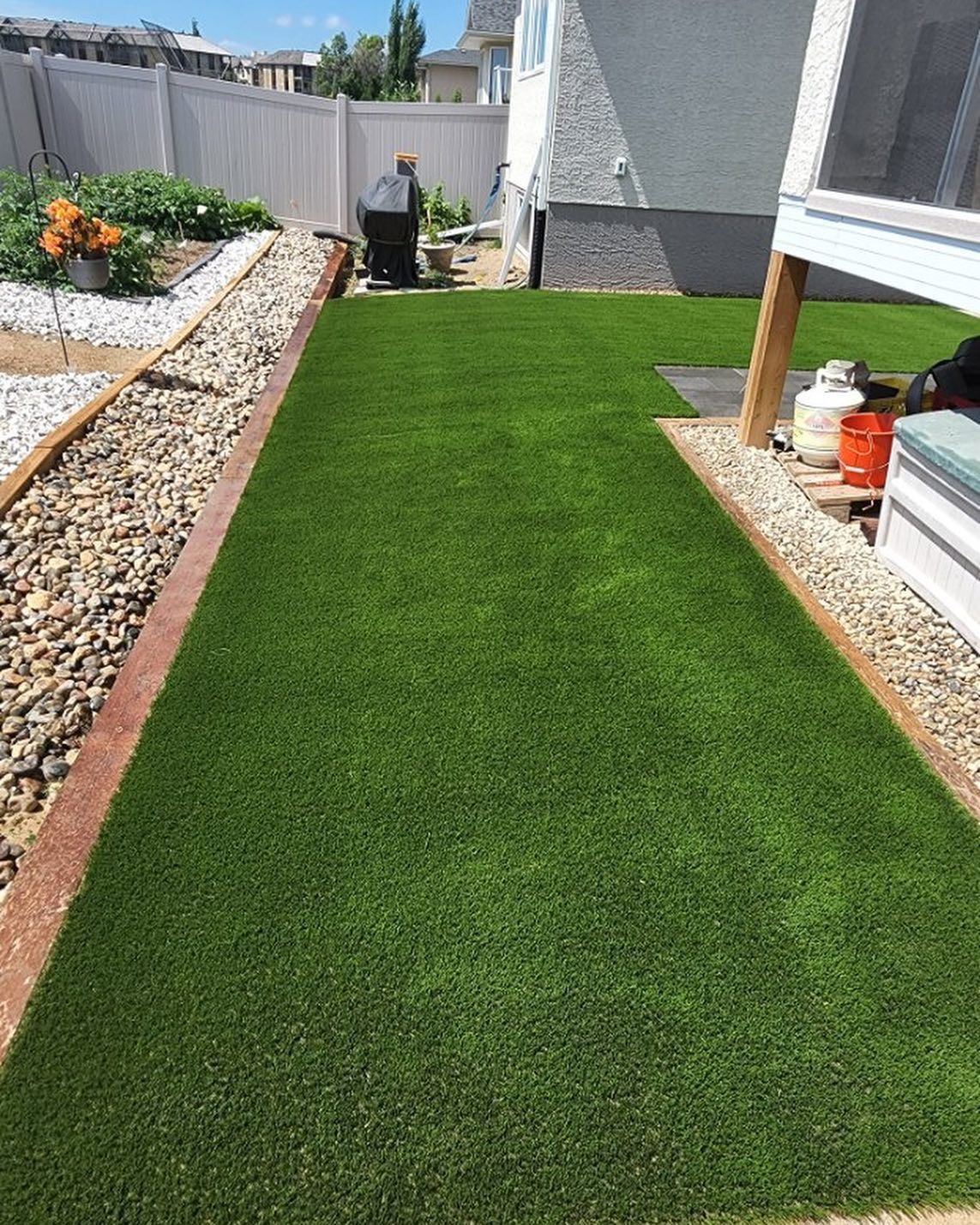 A lawn with a walkway leading to it and a house in the background.