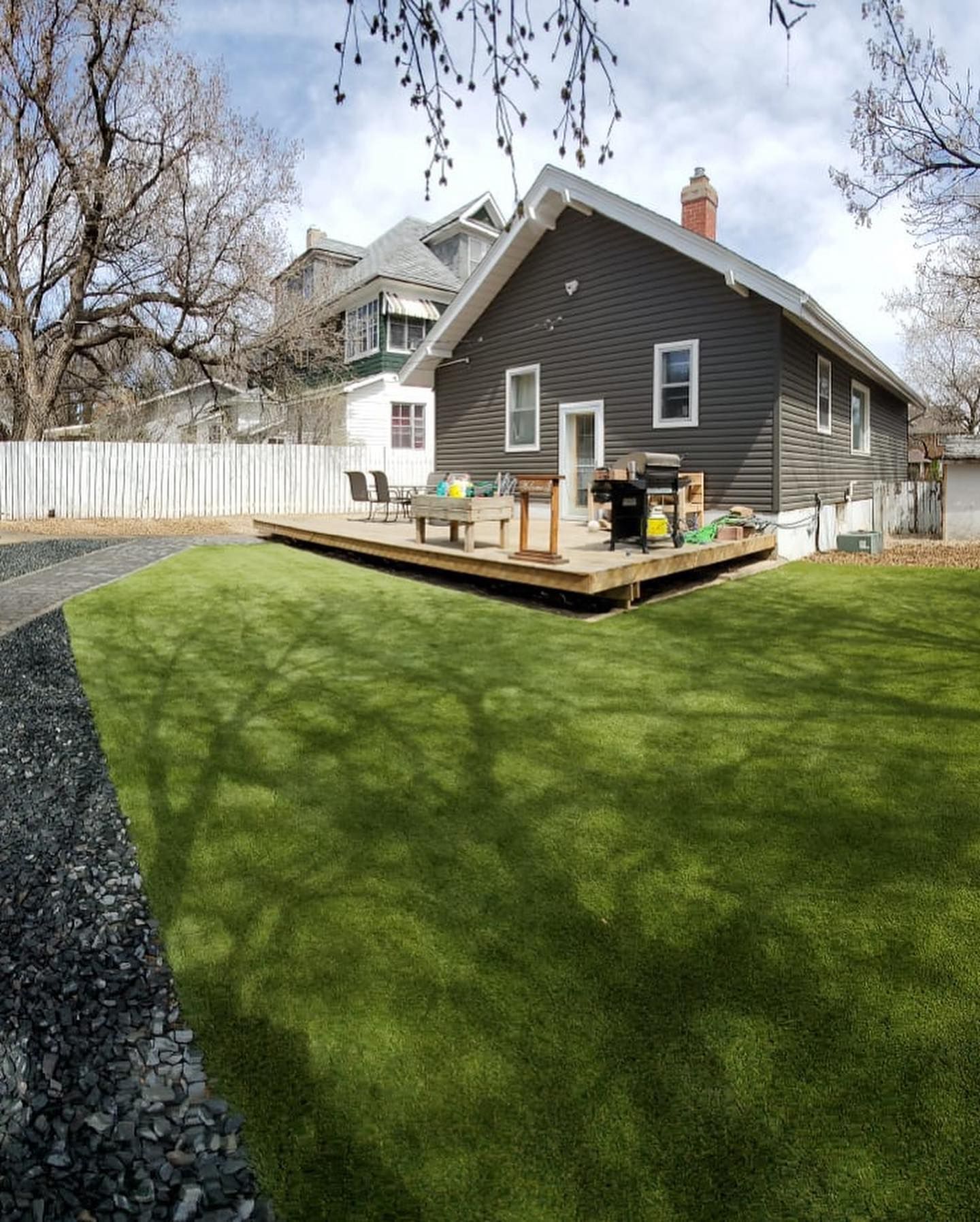 A man is mowing a lush green lawn in front of a house.