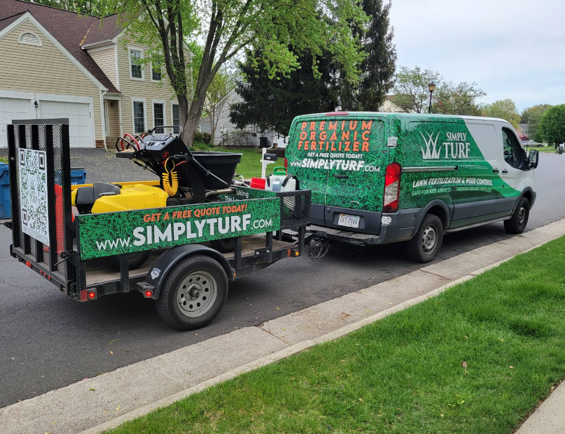 A man is mowing a lush green lawn in front of a house.