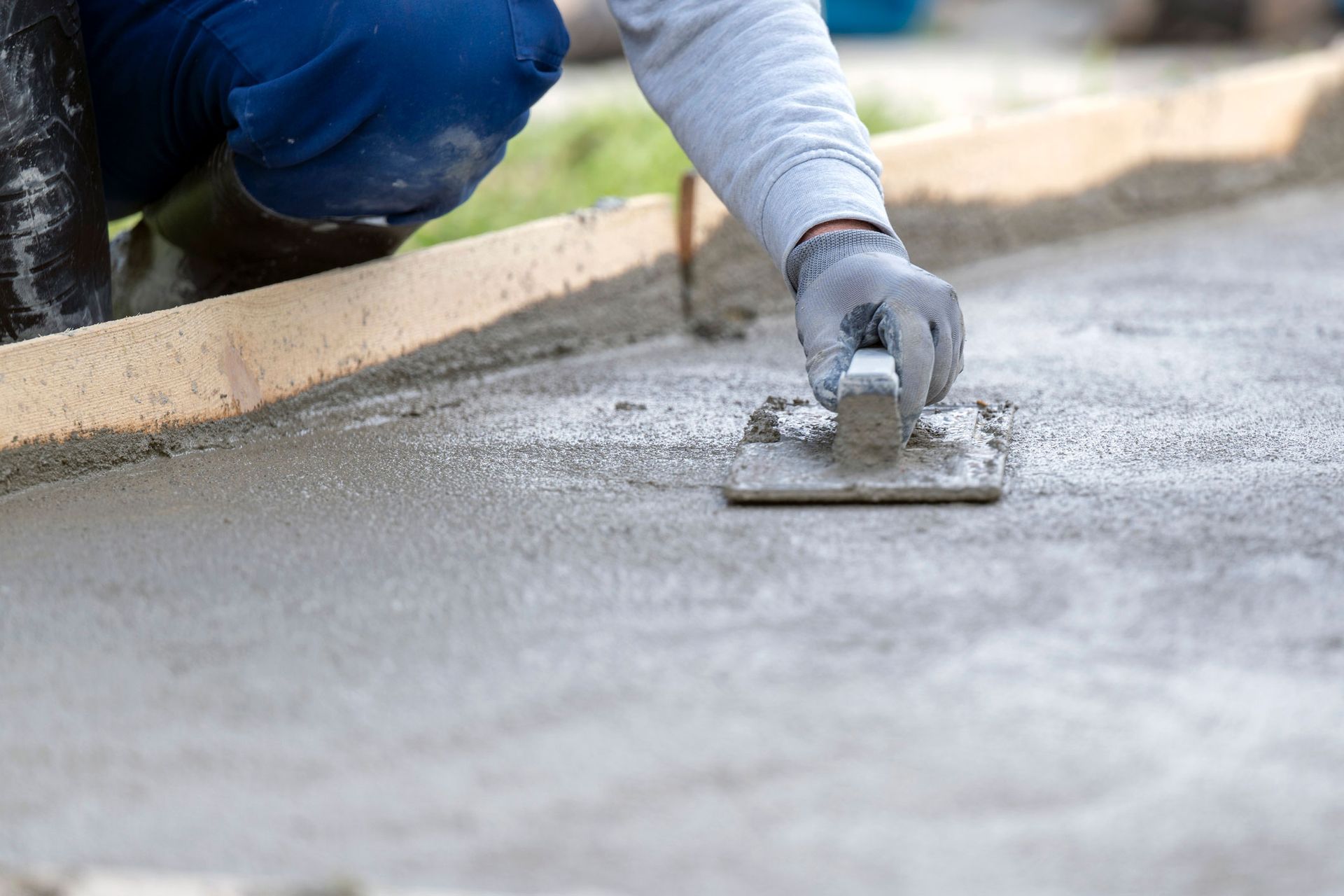Concrete service contractor in Knoxville, TN, smoothing out freshly poured concrete with trowel and plasterer.