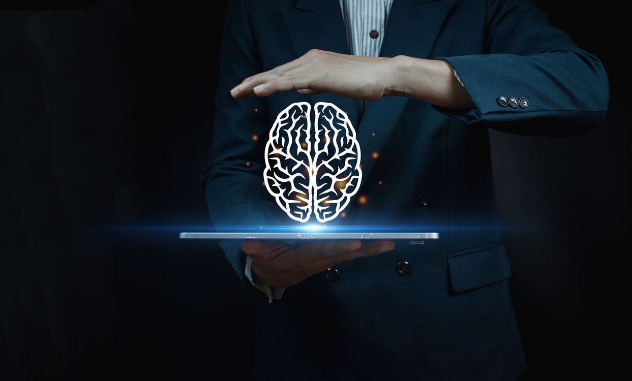 A man in a suit is holding a tablet with a brain coming out of it.