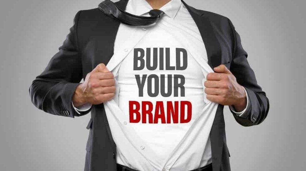 A man in a suit is ripping his shirt open to reveal a shirt that says `` build your brand ''.