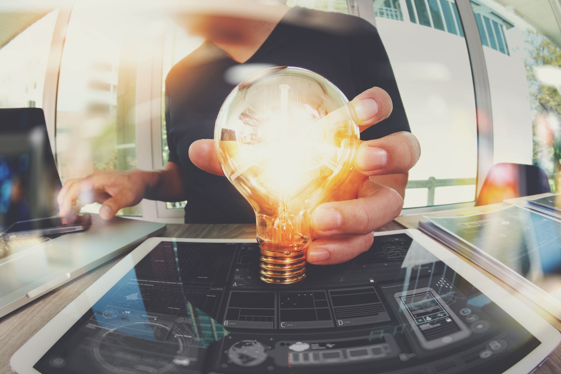 A man is holding a light bulb in his hands while sitting at a table.