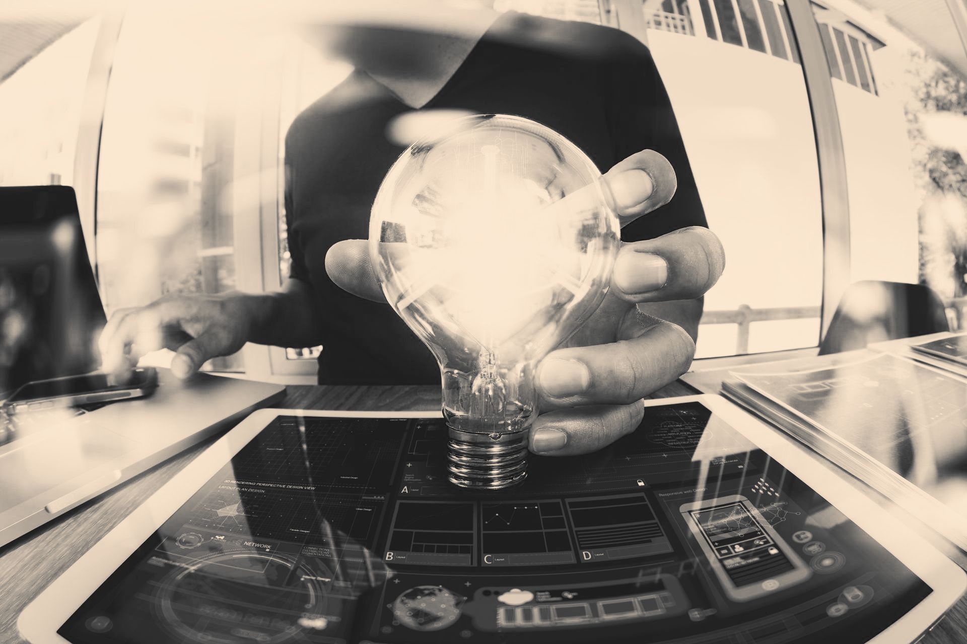A man is holding a light bulb over a tablet