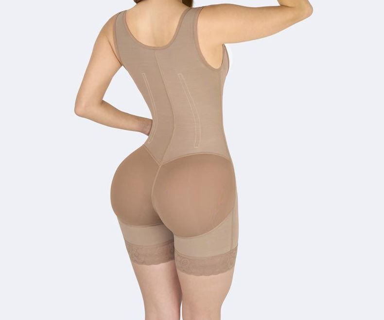 Woman wearing a beige body shaper garment with padded hips, posing from the back.
