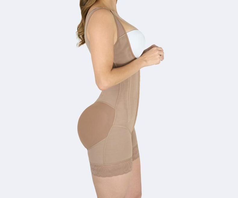 Woman wearing a tan full-body shapewear garment, with a built-in buttock enhancement.