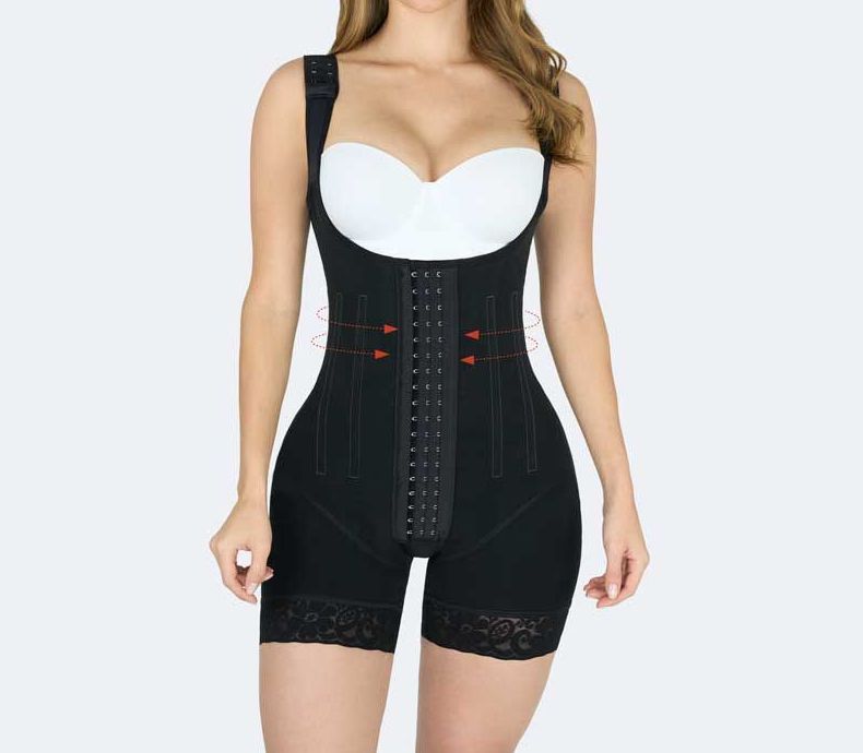 Woman wearing a black shapewear bodysuit with adjustable straps, hook closures, and lace trim on shorts.