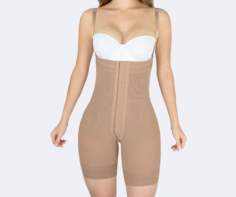 Woman wearing a tan full-body shapewear garment with hook-and-eye closures and adjustable straps.