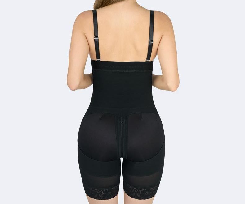 Woman wearing a black shapewear bodysuit. The bodysuit has a high waist, shorts, and adjustable straps.