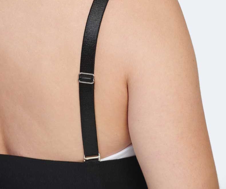 Back view of a person wearing a black dress with an adjustable black strap and silver buckle.