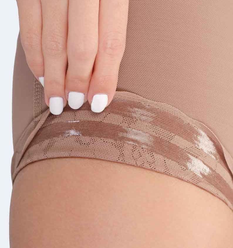 Hand adjusting shapewear at thigh, beige fabric with lace detail.
