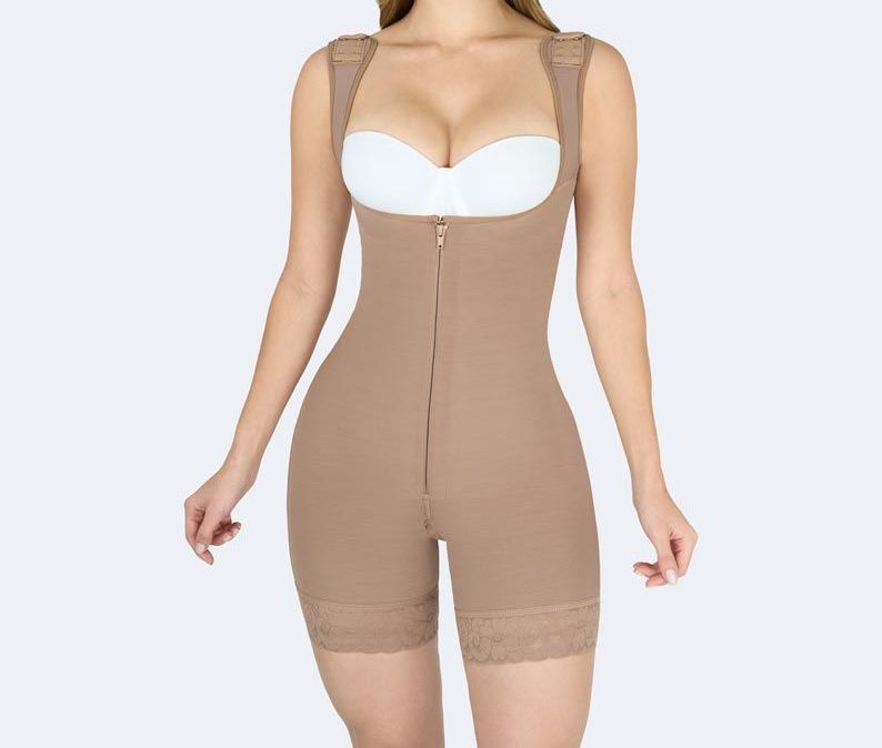 Tan compression bodysuit with front zipper, open bust, and lace trim on the legs.