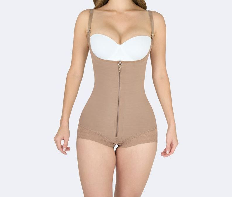 Woman wearing a beige shapewear bodysuit with adjustable straps, standing against a white backdrop.
