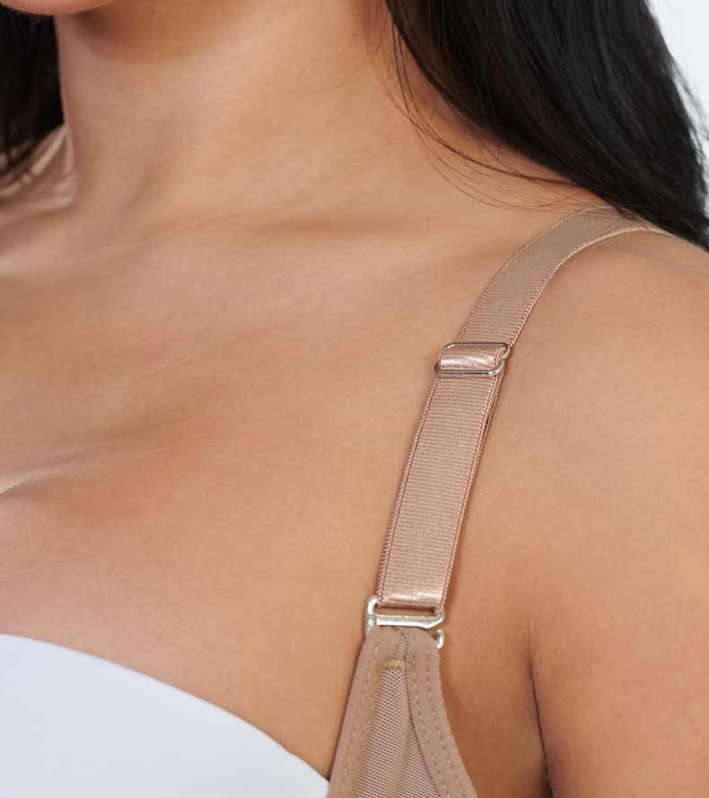 Close-up of a person's shoulder and a tan bra strap with a metal adjuster.