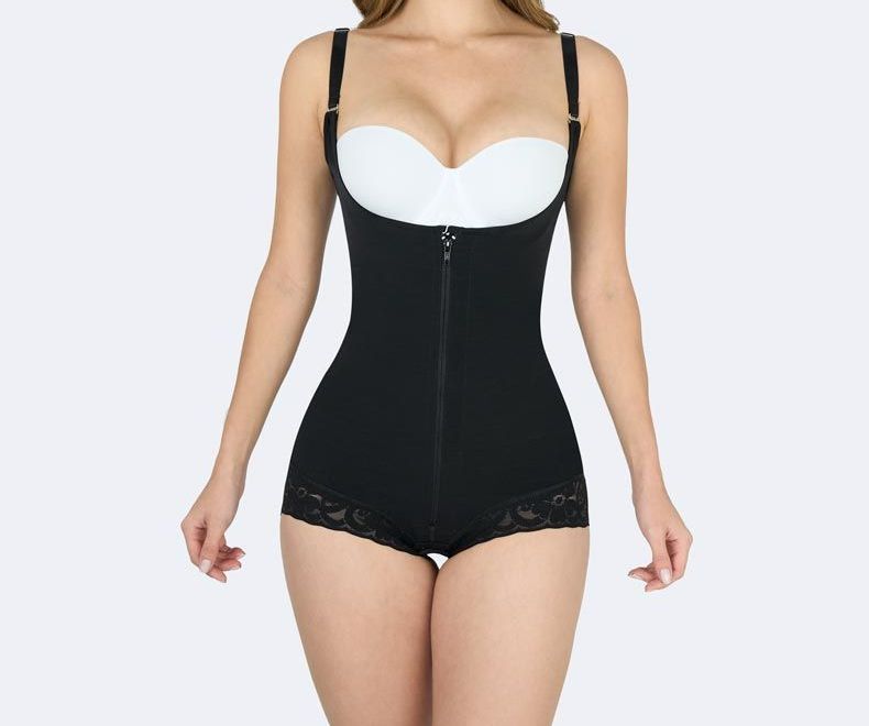 Woman wearing a black shapewear bodysuit with adjustable straps, front zipper, and lace trim.