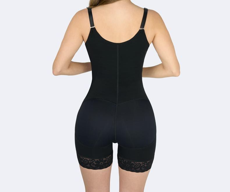 Woman wearing a black shapewear bodysuit. It has adjustable straps, and lace trim on the shorts.