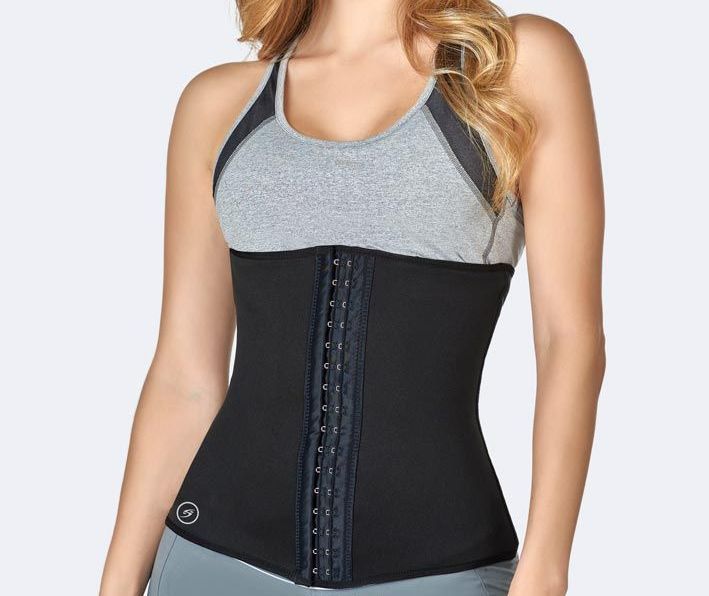 Woman wearing a black waist trainer over a gray sports bra and workout clothes.