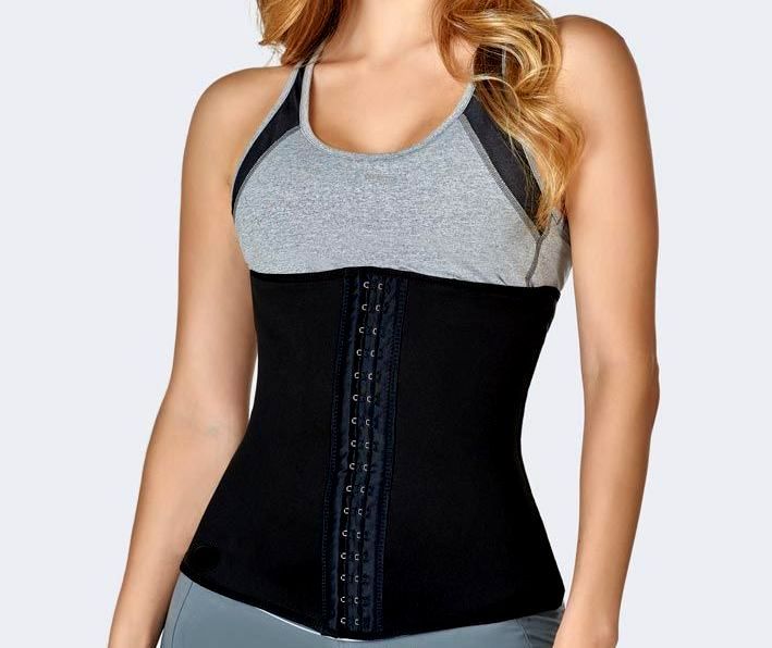 Woman wearing a black waist trainer over a gray sports bra.