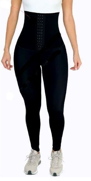 Woman wearing black high-waisted shapewear leggings and sneakers, posing on white background.