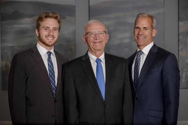 A wooden walkway leading to a gazebo overlooking a body of water at sunset.