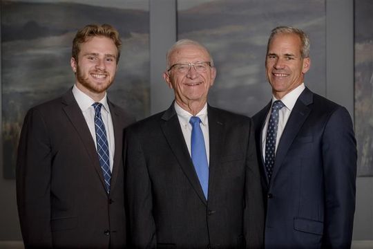A wooden walkway leading to a gazebo overlooking a body of water at sunset.