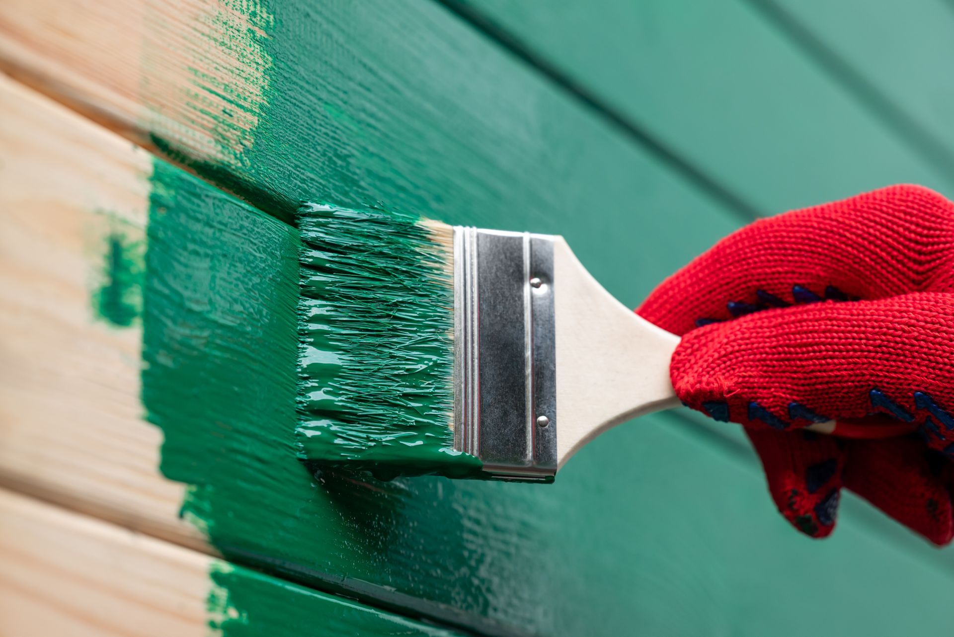 A person is painting a wooden wall with a brush.