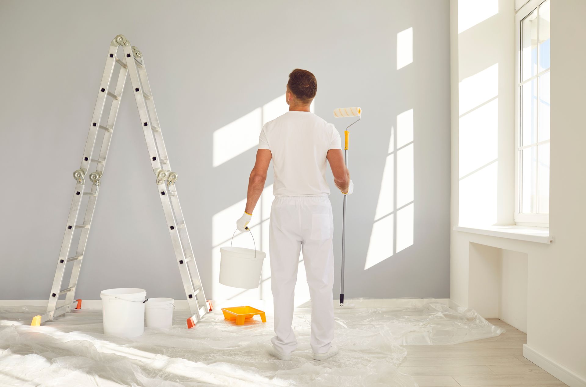 A man is painting a wall in an empty room.