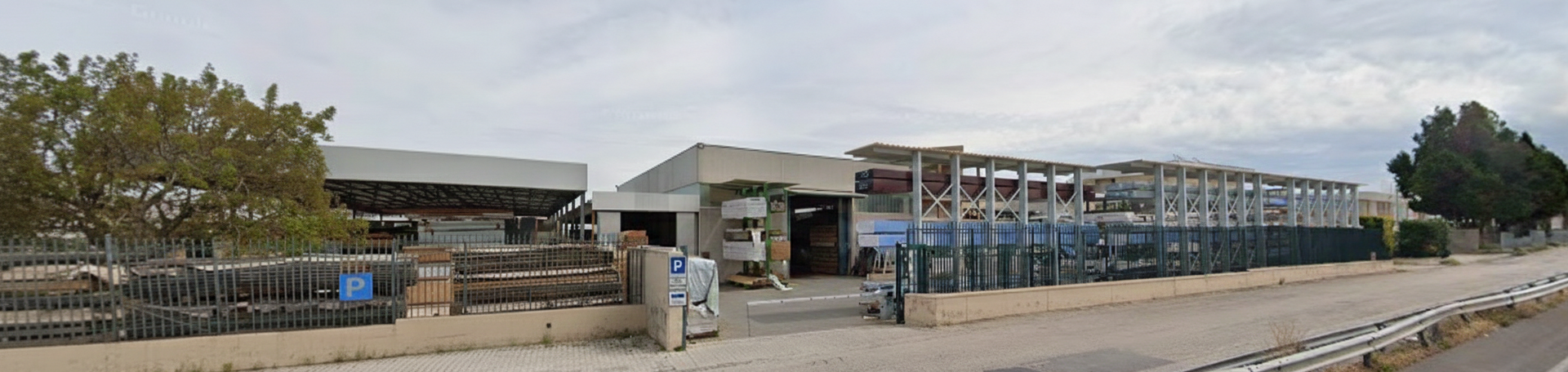 Vista esterna di un edificio con cielo nuvoloso. L'edificio ha un ingresso aperto con una persona.