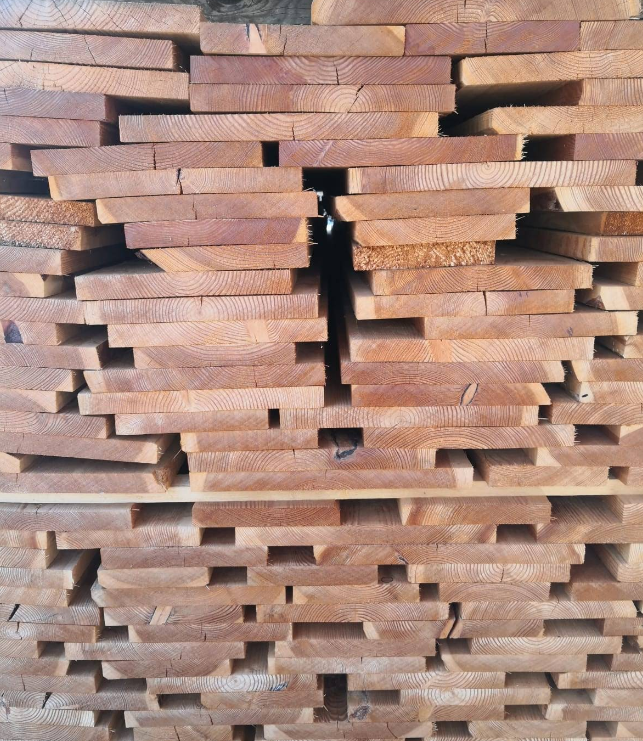 Pila di assi di legno di colore bruno-rossastro, disposte strettamente e con spazi tra loro.