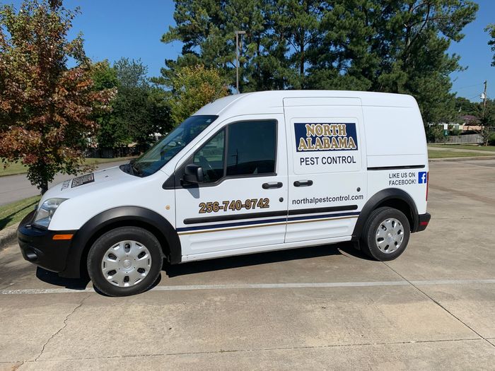 A white north alabama pest control van is parked in a parking lot.