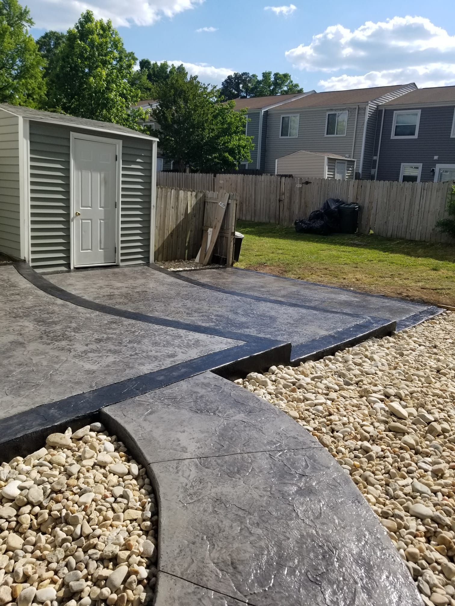 A concrete driveway with a shed in the background.