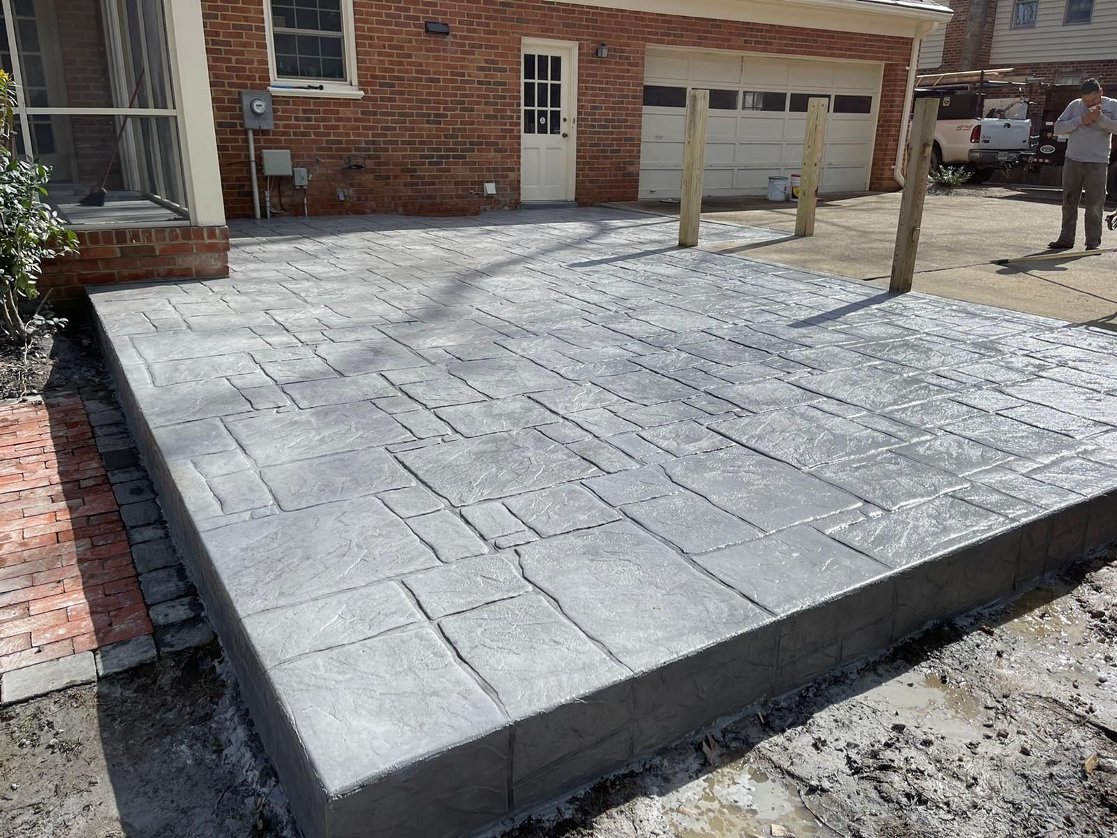 A concrete driveway is being built in front of a brick house.