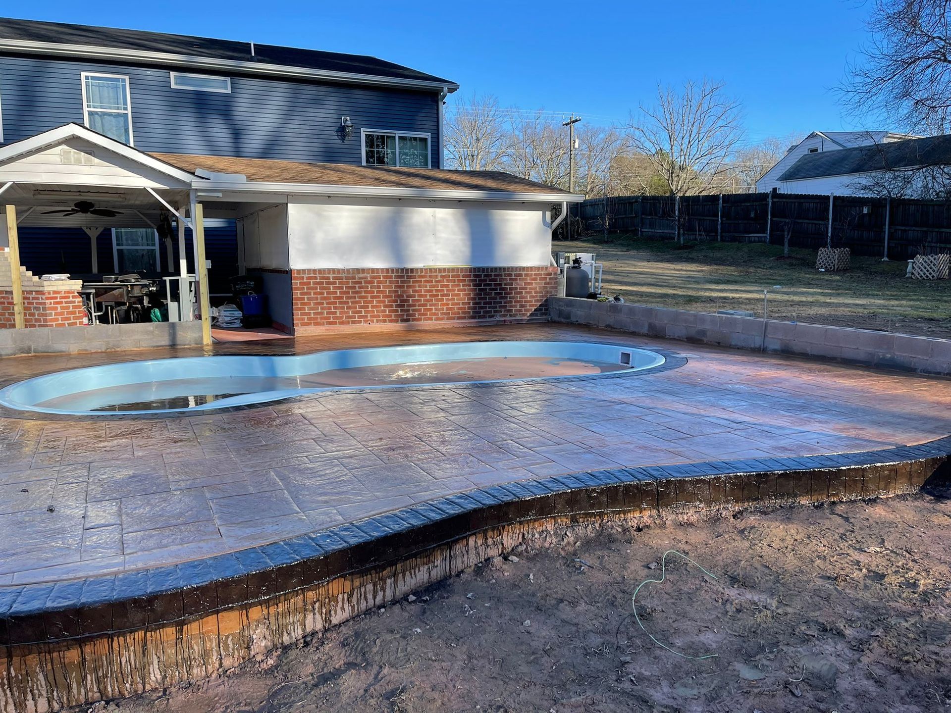 A swimming pool is being built in the backyard of a house.