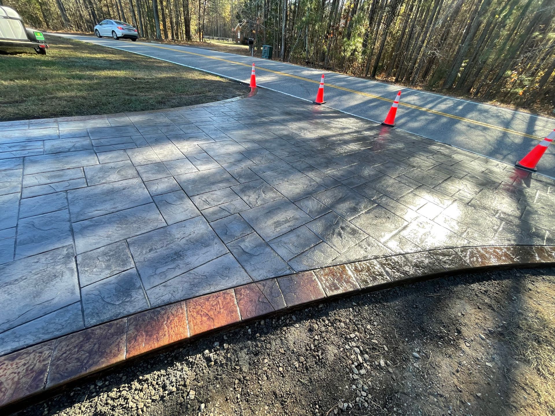 A concrete driveway with red cones on the side of it.