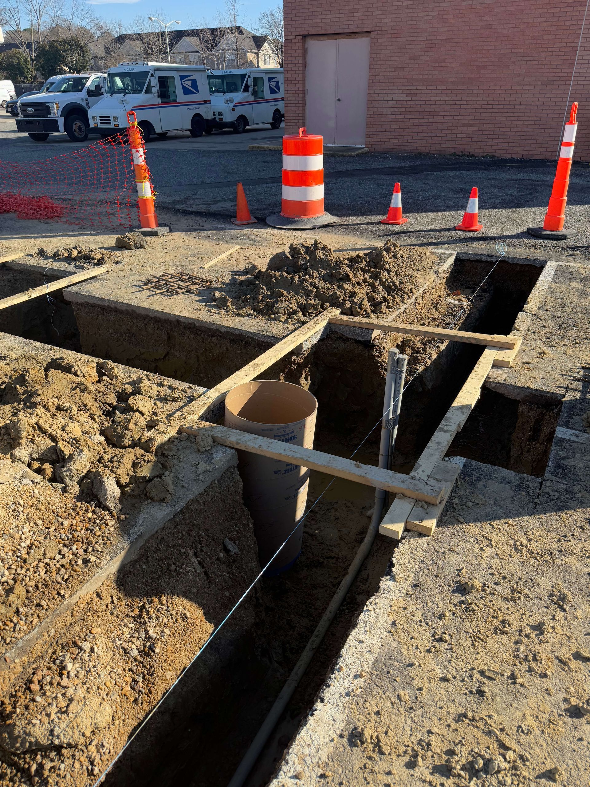 A construction site with a lot of dirt and a brick building in the background.